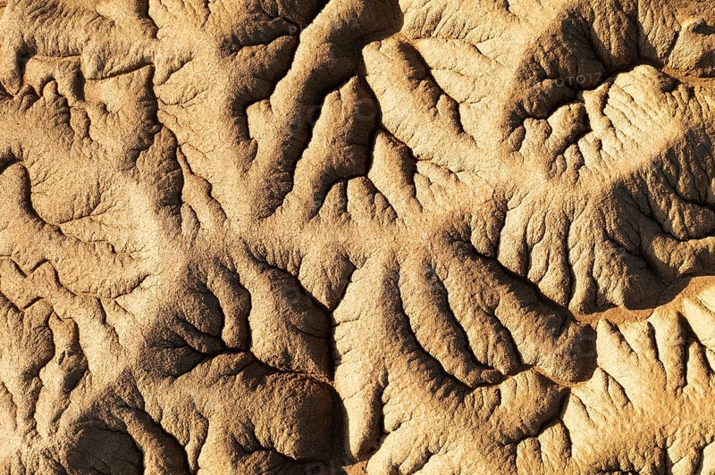 Aerial view capturing detailed patterns formed in the desert The shadows enhance the texture of the sand dunes, creating a natural abstract design in earthy tones