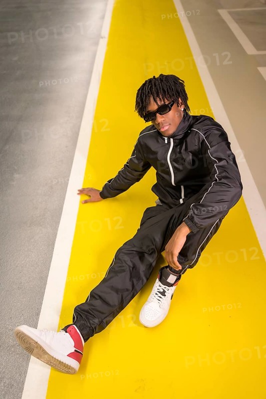 Vertical photo of a cool african artist man sitting on a garage