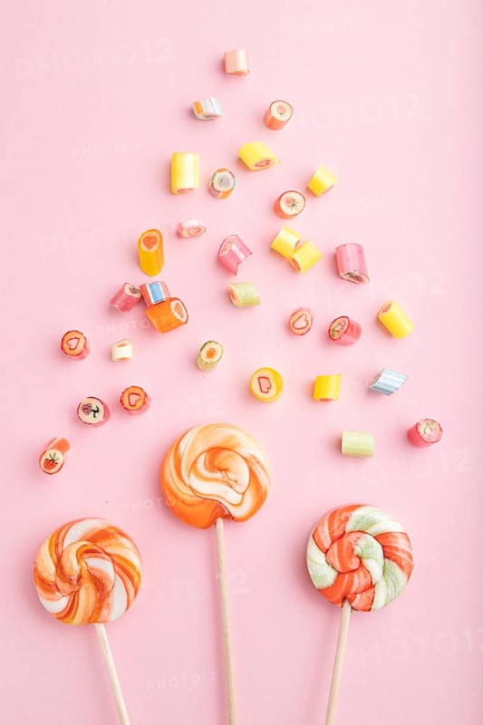 Various caramel candies on pink pastel background. close up, top view, flat lay