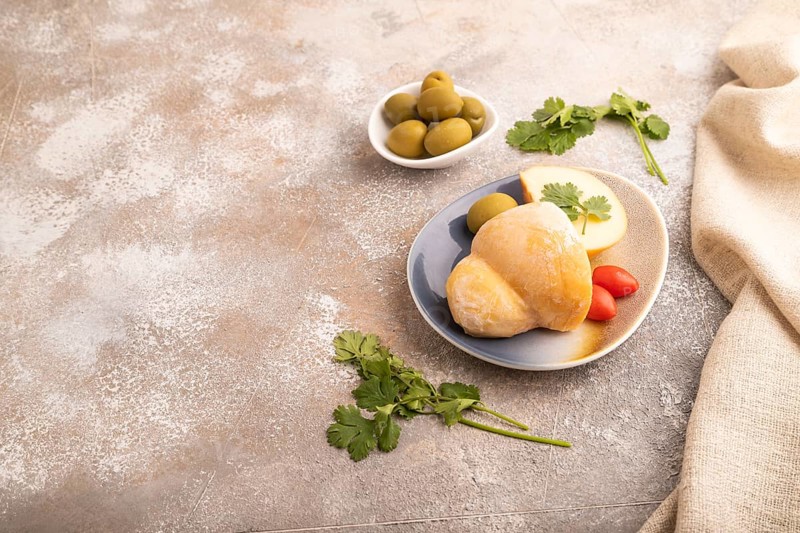Smoked Mozzarella cheese, with tomatoes and olives on brown concrete background and linen textile, side view, copy space