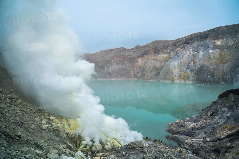 Dense sulfuric steam ascends from the turquoise crater lake of Ijen volcano in Indonesia, creating a surreal and captivating volcanic landscape