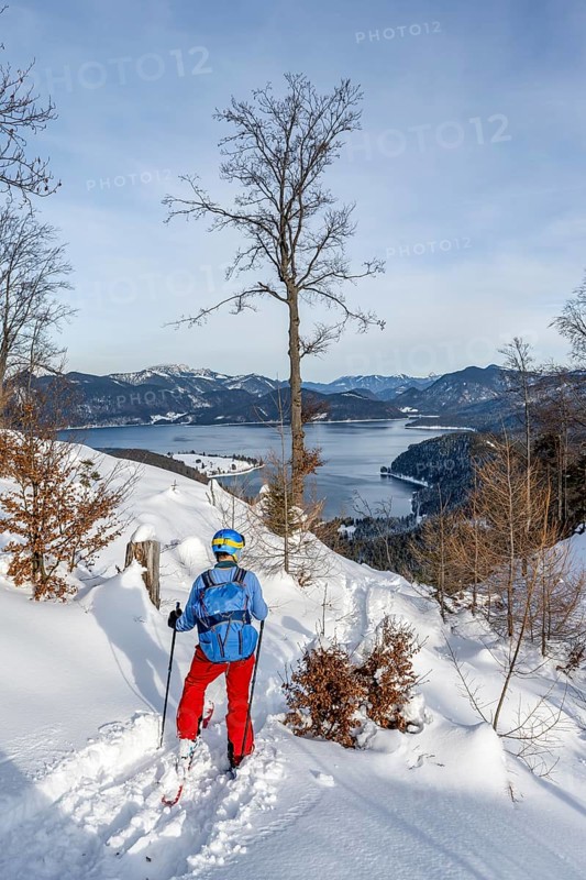 Skiers skiing down the Simetsberg, view of Walchensee and mountain panorama, Estergebirge, Bavarian Prealps, Bavaria Germany