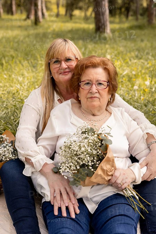 A touching scene of a mother and daughter sitting in a green park, sharing a peaceful day. They hold bouquets of flowers, symbolizing love and familial bonds