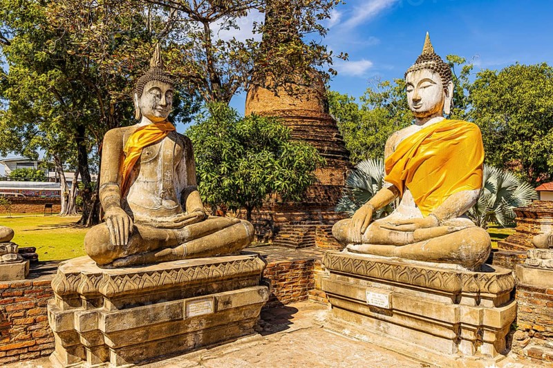 Stone Buddha statues decorated with yellow cloths, historic Buddhist temple complex, Ayutthaya, Thailand