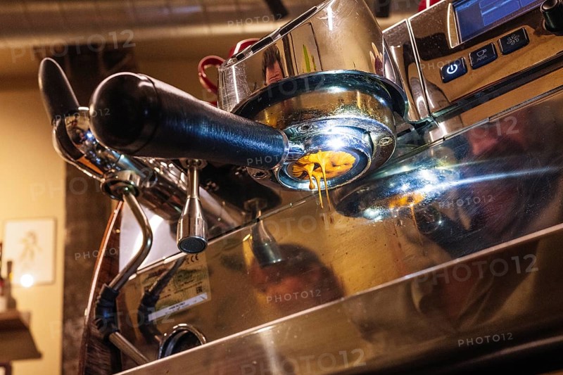 An intricate view of an espresso machine brewing specialty coffee. The rich, golden espresso flows smoothly, highlighting the art and precision of coffee making