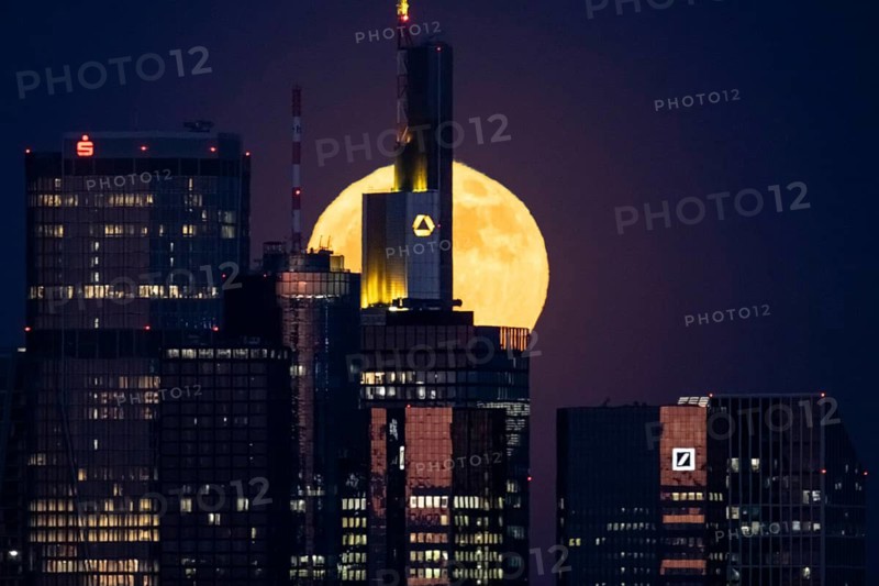 The full moon passes behind the Frankfurt banking skyline, Frankfurt am Main, Hesse, Germany