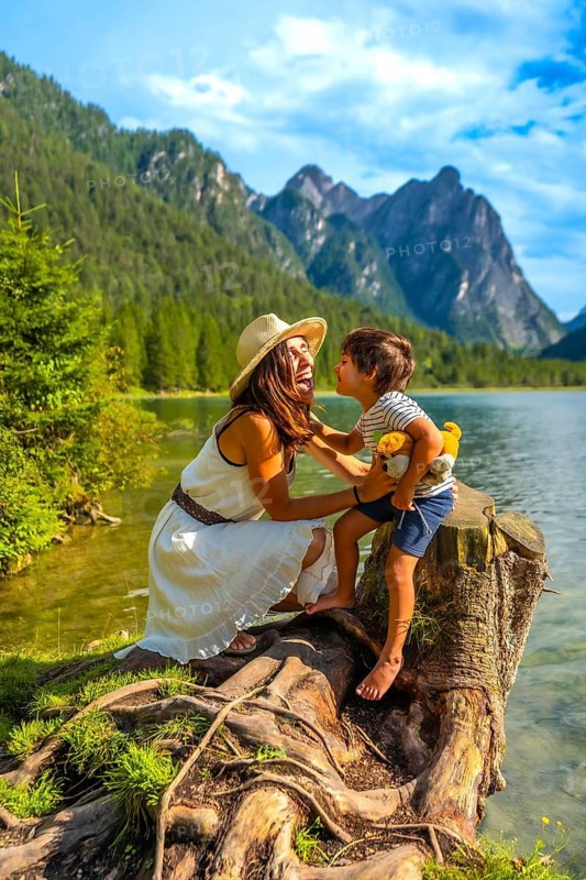 Tourists enjoying summer holidays at lake dobbiaco, surrounded by the stunning scenery of the dolomites in italy