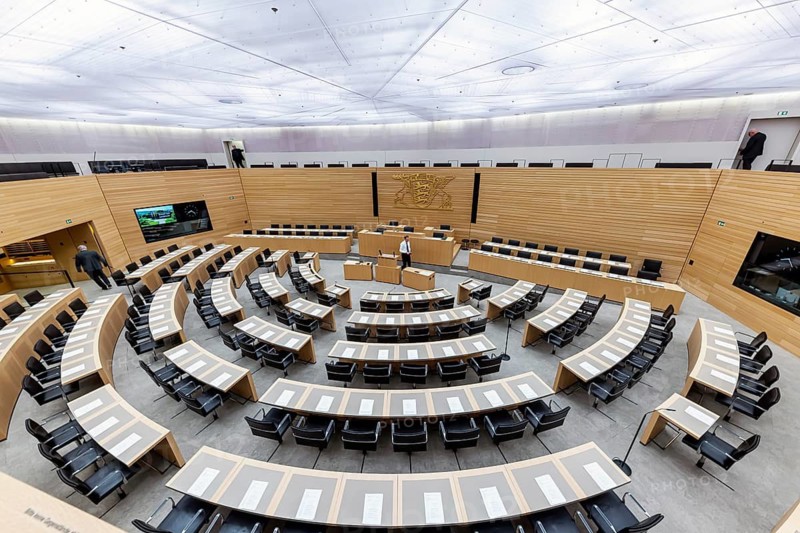 Plenary hall deserted with the seats of deputies and the government bank. Behind it is the coat of arms of the federal state. The state parliament of Baden-Württemberg is the state parliament based in Stuttgart, Baden-Württemberg, Germany