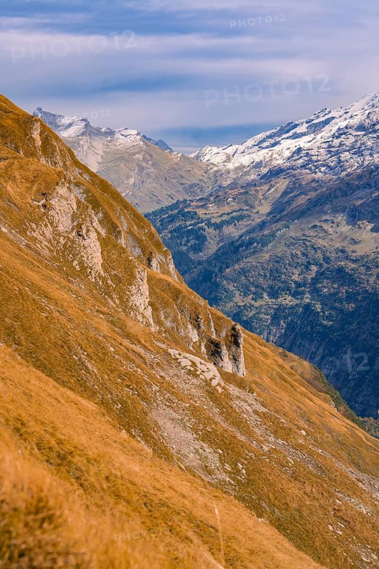 A rocky mountainside stretches across a wide valley under a slightly cloudy sky, Planplatten, Switzerland