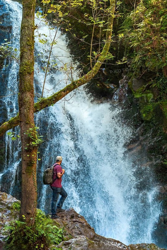A man with his back turned at the impressive Xorroxin waterfall in northern Navarra, near the village of Errezil