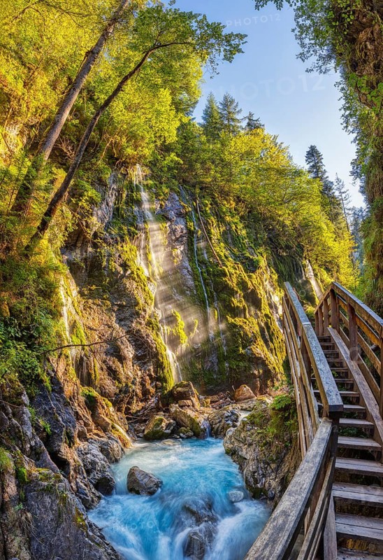 An idyllic hiking trail with a wooden staircase leads along a waterfall in the middle of a green landscape, Wimbachklamm gorge