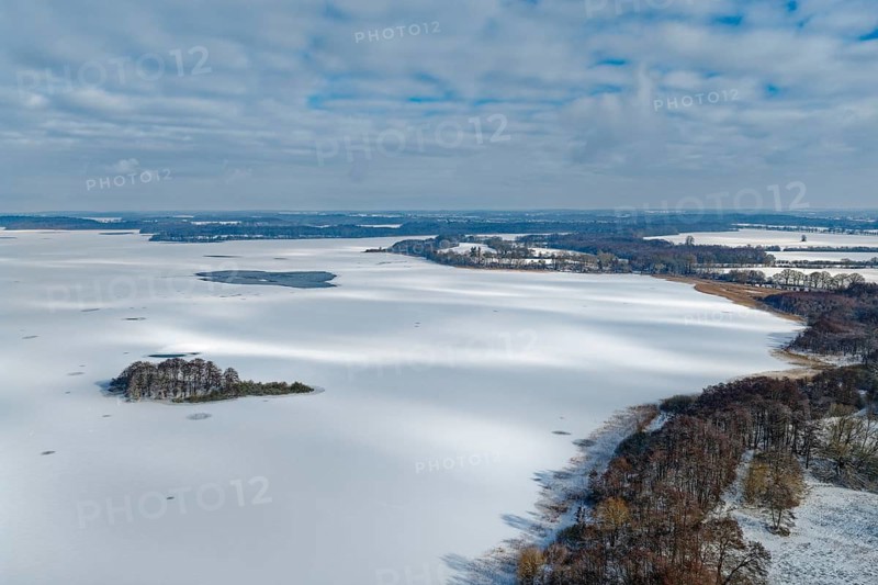 There is snow on the frozen Schaalsee near Zarrentin in the UNESCO Schaalsee Biosphere Reserve. In front is the island of Möwenburg. aerial view. Zarrrentin, Mecklenburg-Western Pomerania, Germany
