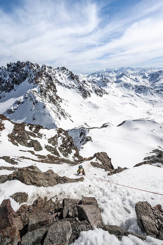 Mountaineer climbing up a steep snow slope, secured by a rope, ascent to the summit of Piz Grialetsch in winter, view of mountain panorama with Piz Vadret with snow, Grisons Haute Route, Albula Alps, Rhaetian Alps, Grisons, Switzerland