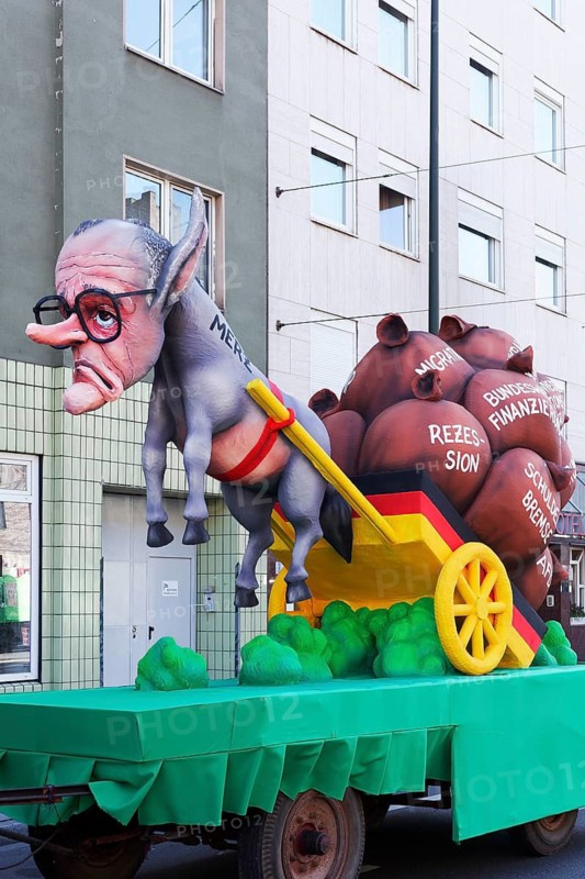 Chancellor candidate Friedrich Merz as a donkey figure in front of a cart with heavy sacks, debt brake, recession, migration, papier-mâché figure, theme float by Jacques Tilly, Rosenmontagszug 2025, Düsseldorf, Rhineland, North Rhine-Westphalia, Germany