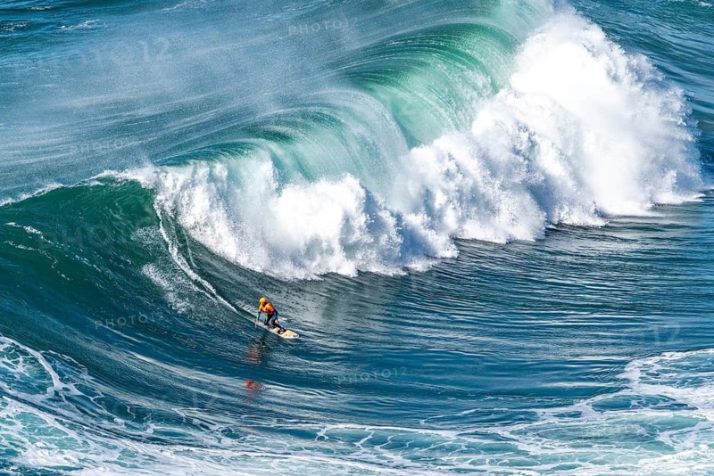 Surfers with their jet ski pilots in the Atlantic waves below Farol de Nazaré, Forte São Miguel, known as a surfer hot spot with monster waves between November and February of each year, Nazaré, Portugal