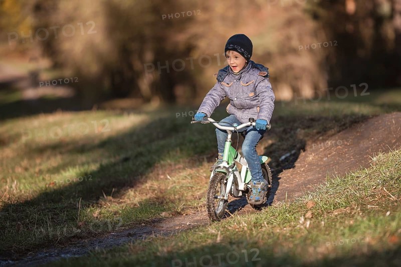 Six years old boy rides bicycle from the hill in the park