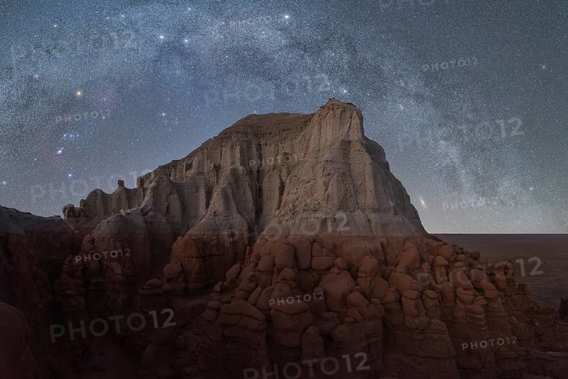 A starry night sky illuminates the unique rock formations in Utah, USA, highlighting a landscape of rugged beauty and serene desolation