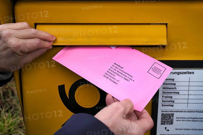 Woman throws ballot letter into mailbox, ballot envelope, bright red, pink, postal ballot, official absentee ballot documents, election, parliamentary election, state election 2026, Stuttgart, Baden-Württemberg, Germany