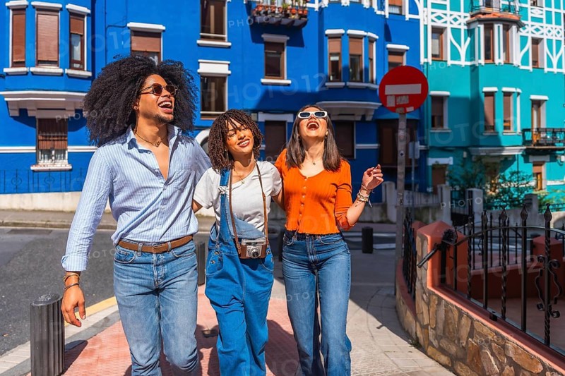 Three joyful friends walking together down a vibrant city street, soaking up the sights and sounds of their exciting vacation