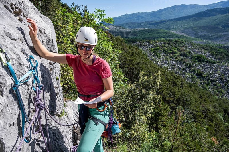 Climber on the rope looking at the topo, multi-pitch climbing, Via la Bellezza della Venere, Garda Mountains, Arco, Trentino-Alto Adige, Italy