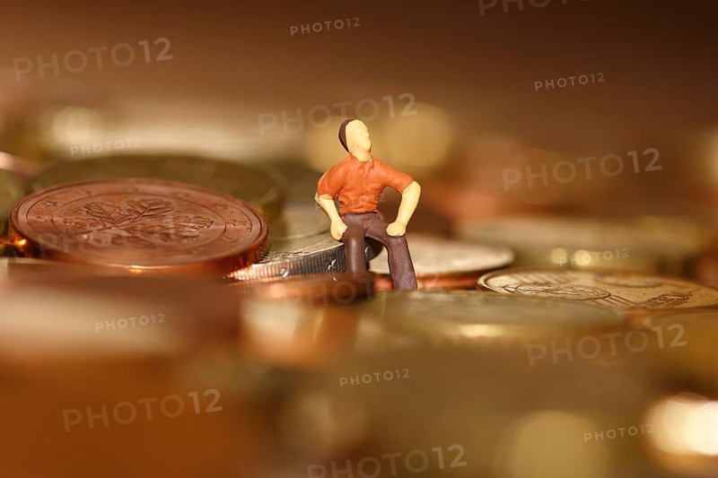 Miniature man sitting among euro coins, North Rhine-Westphalia, Germany