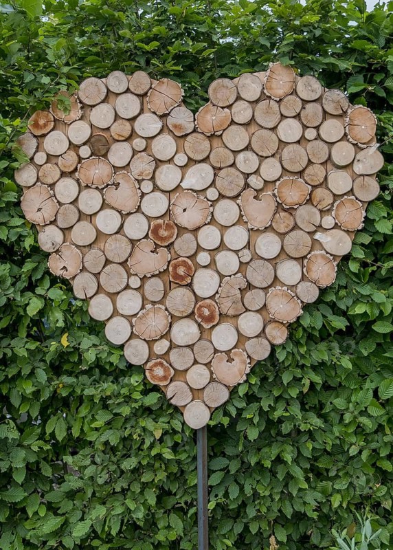 Wooden discs in the shape of a heart in front of dense green leaves, Münsterland, North Rhine-Westphalia, Germany