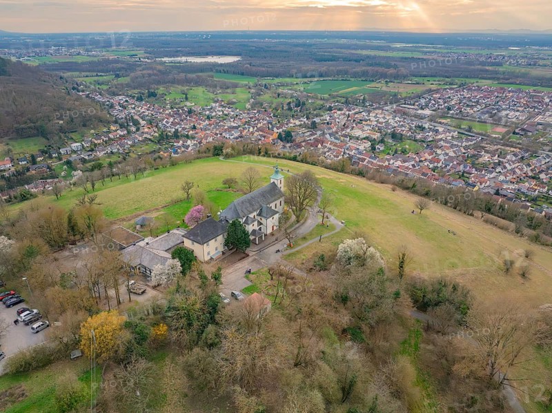 Wide bird's eye view of a hilly village backdrop with a striking building surrounded by nature, Michelsberg, Bad Münstereifel