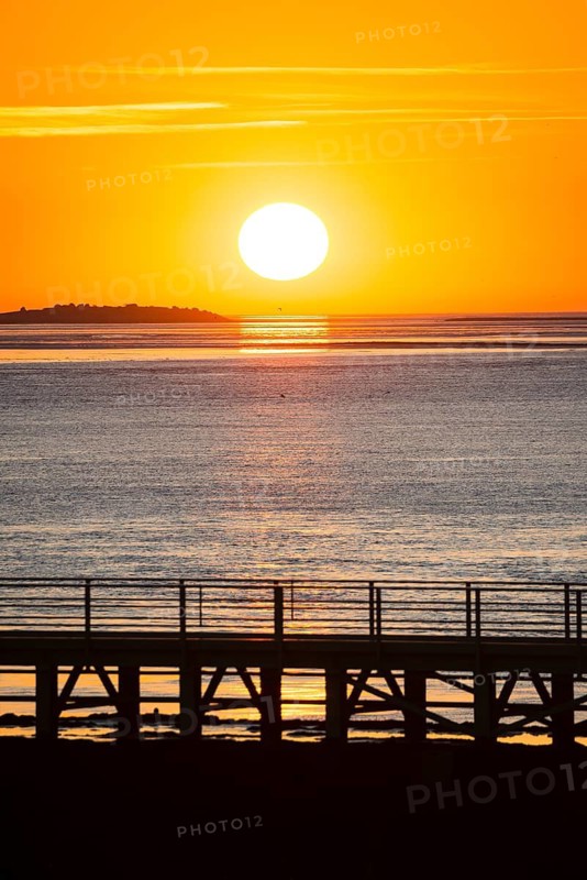 Silhouette of a jetty, pier free canal, in front of a picturesque, golden, breathtakingly beautiful sunset over the sea, island Langlütjen II far away, sun ball just above the horizon, orange glowing cloudless sky, wide sea in soft colours, calm atmosphere, mouth of the Weser into the North Sea, Outer Weser, Bremerhaven, Land Bremen, Germany