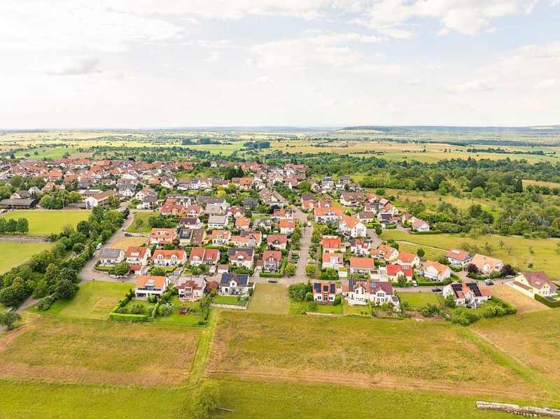 Town view with many houses in a residential area, surrounded by fields and under a slightly cloudy sky, Kieselbronn, Germany