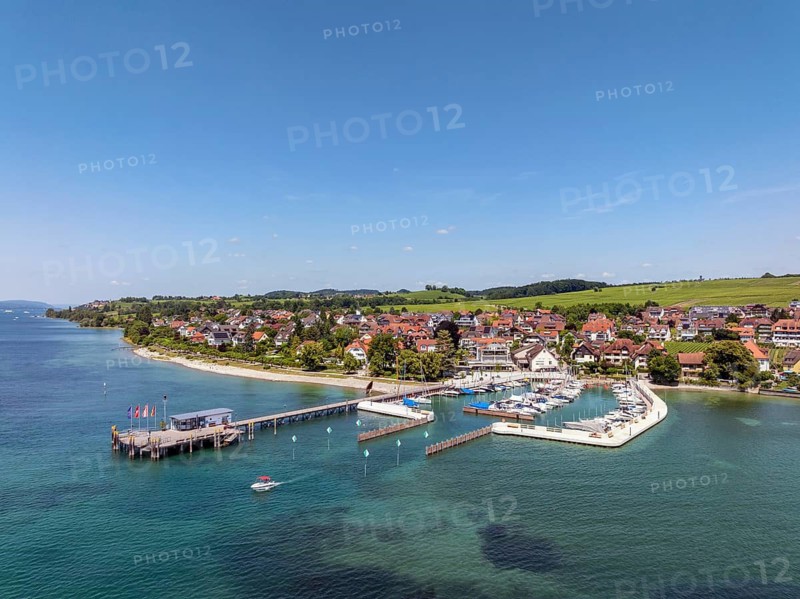 Luftbild von der Bodenseegemeinde Hagnau, Winzerdorf und beliebter Ferienort am Bodensee, dahinter Rebhänge, auf denen hauptsächlich die Weinsorten Müller Thurgau und Blauer Burgunder angebaut werden. Am Seeufer der am 23.Mai 2025 eingeweihte, neue Westhafen, Yachthafen mit der Schiffanlegestelle, Bodenseekreis, Baden-Württemberg, Deutschland