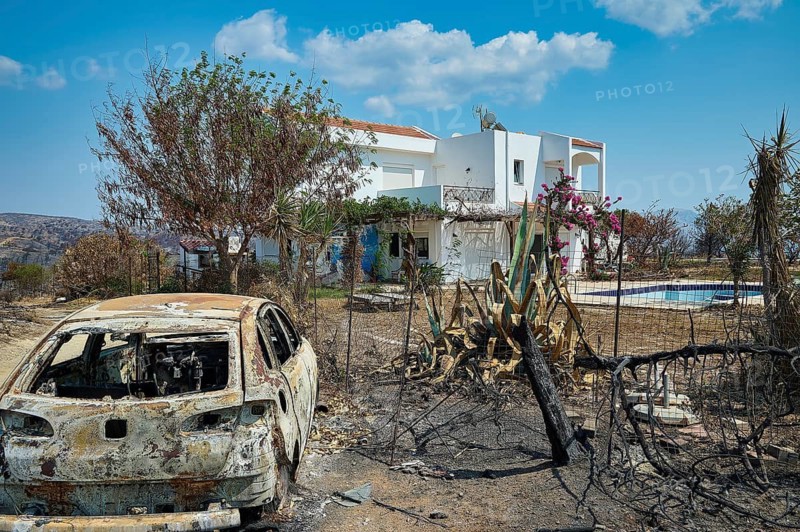 A burnt car next to a house with a pool, surrounded by burnt vegetation and a blue sky, forest fires, summer 2023, forest fire damage, Kiotari, Rhodes, Dodecanese, Greek Islands, Greece