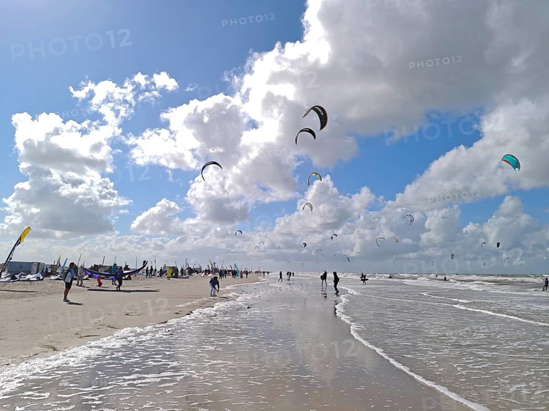 California kitesurfing Masters 2025 at the edge of the UNESCO World Heritage Wadden Sea, North Sea, kitesurfing sport, flying kites, spectators, fun, competition, strong wind, whitecaps, beach, summer, sunshine, blue sky, white clouds, Ording, Sankt Peter-Ording, Schleswig-Holstein, Germany