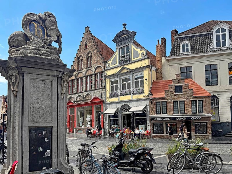 Lively square with cafés, bicycles and a decorative statue, Bruges, West Flanders, Belgium