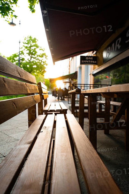 A sun-drenched evening in a street with wooden benches and an outdoor café, Berlin, Germany