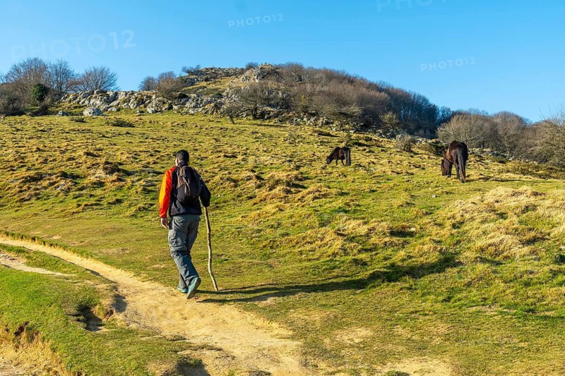 A man walking on the path climbing to the top of Mount Ernio or Hernio in Gipuzkoa, Basque Country