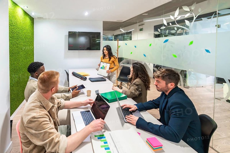 Marketing team working together in a modern office, using laptops and analyzing graphs during a productive meeting