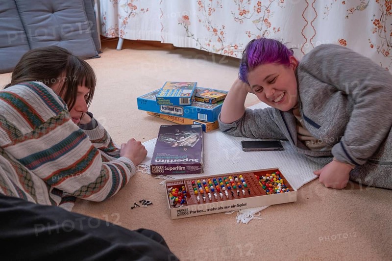 Two young woman playing a parlour game on the carpet in the living room, Bavaria, Germany