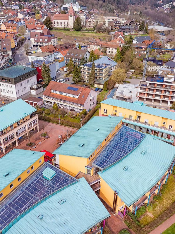 View over colourful roofs of commercial buildings in a hilly small town with trees, Bad Liebenzell, district of Calw, Germany