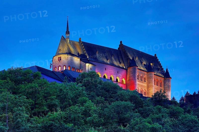Vianden Castle, hilltop castle illuminated in the colours of the Luxembourg flag for the bank holidays, Vianden, Grand Duchy of Luxembourg