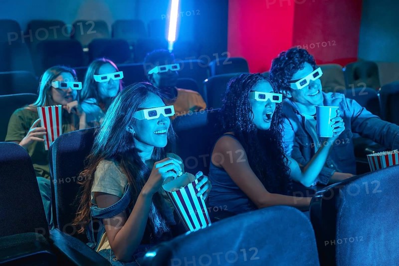 Diverse group of friends enjoying a 3d movie at the cinema, wearing 3d glasses, eating popcorn and having fun