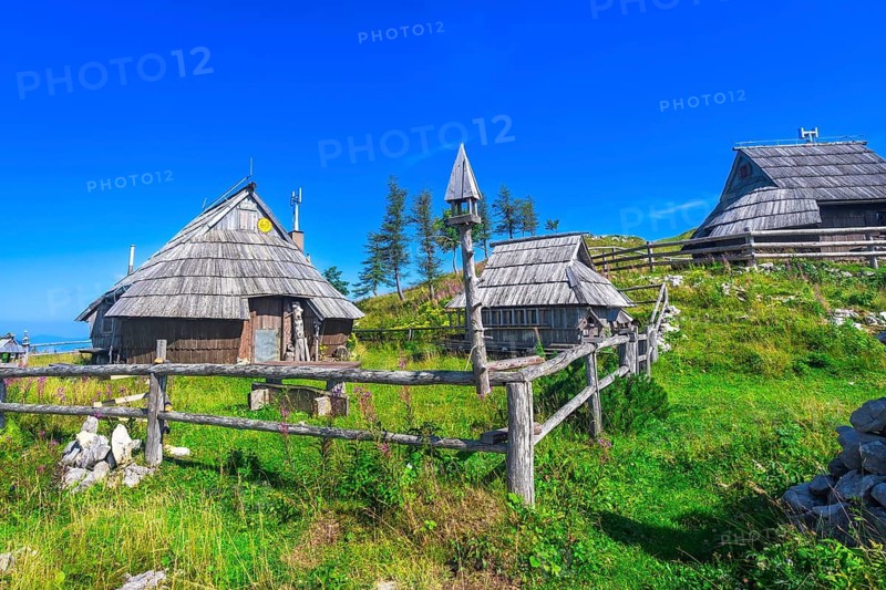 Scenic wooden houses scattered across the idyllic landscape of velika planina, overlooking the logarska dolina valley under the warm summer sun