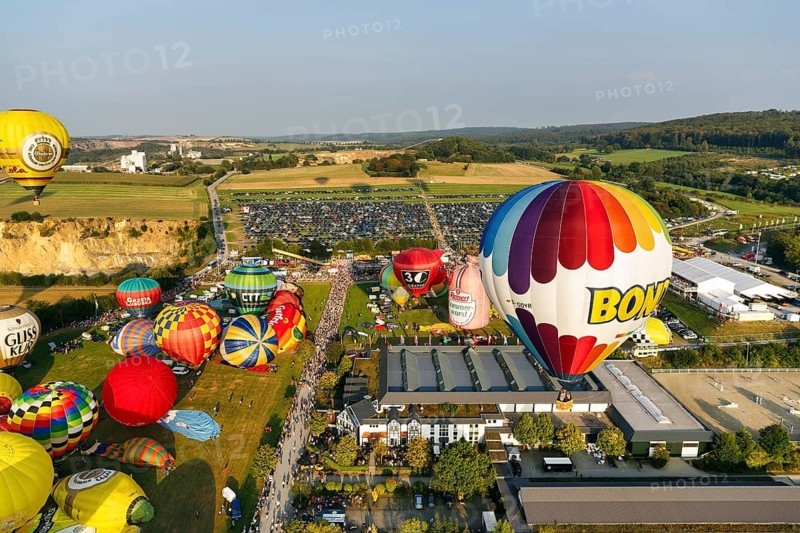 Colourful hot air balloons at mass launch, crowd on fairground, Hot Air Balloon Festival, 26th Warsteiner International Montgolfiade, aerial view, Warstein, Sauerland, North Rhine-Westphalia, Germany