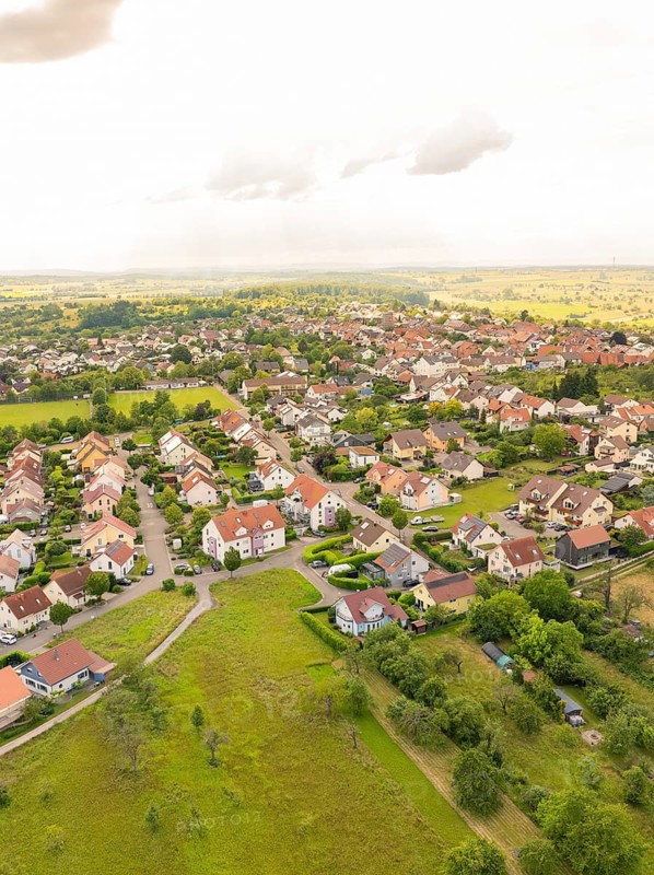 Densely built-up residential area with numerous houses and gardens, surrounded by green countryside and under a cloudy sky, Kieselbronn, Germany