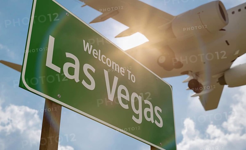 Welcome to las vegas green road sign with low flying airplane just above with landing gear down