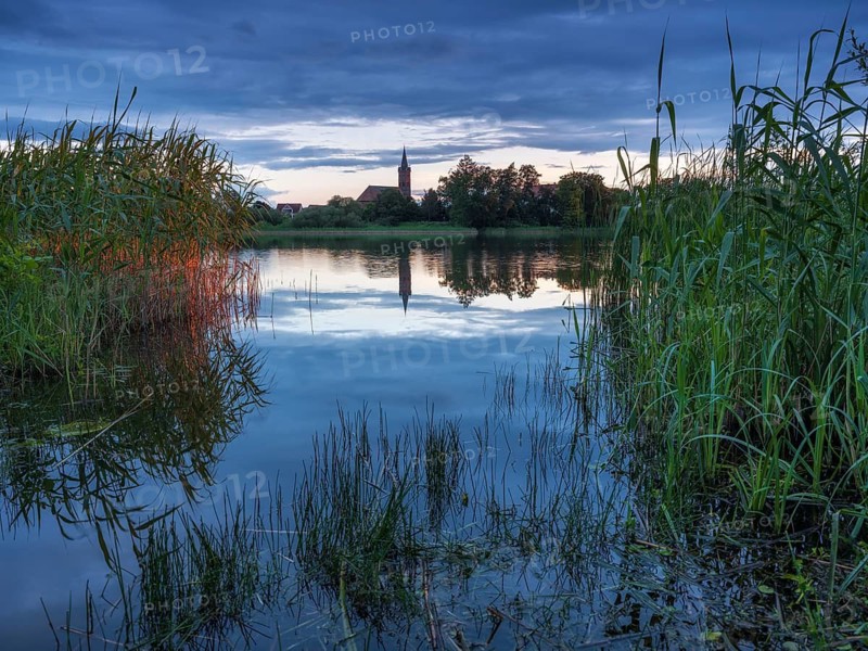 The church of Großkühnau is reflected in Lake Großkühnau at dusk, Garden Kingdom of Dessau-Wörlitz, Dessau-Roßlau, Saxony-Anhalt, Germany
