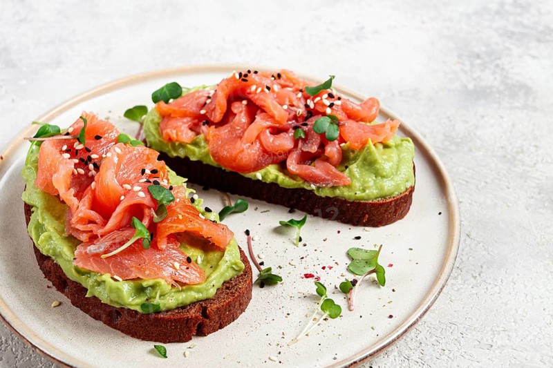 Breakfast, Sandwiches with smoked salmon and avocado, on dark rye bread, with microgreens, on a marble table, homemade, no people