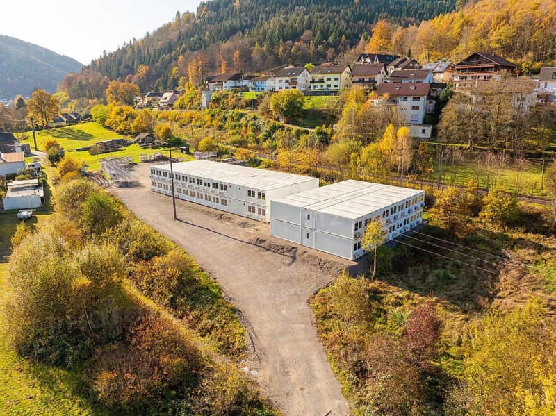 Container building in a natural environment with autumn trees and a village, refugee accommodation Beermiß, Calmbach, Black Forest, Germany