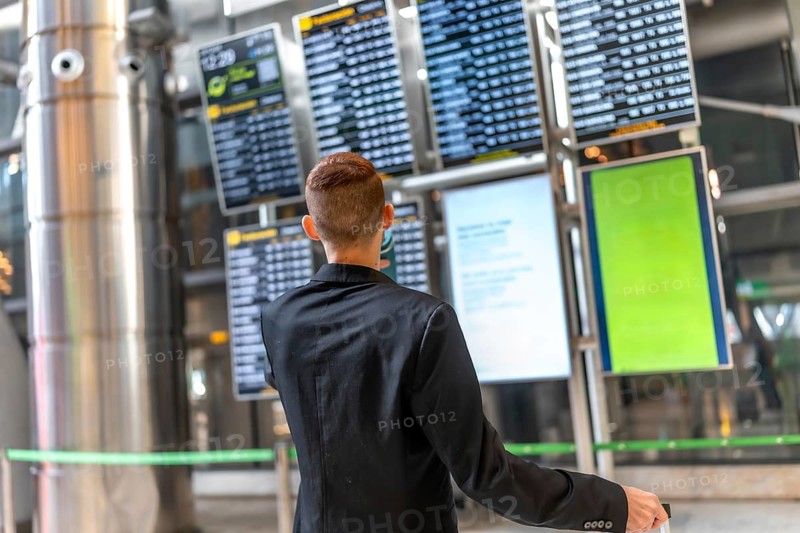 Businessman looking at timetable display while waiting for his flight, travel and business concept