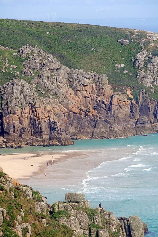 Kleiner Sandstrand eingebettet zwischen steilen Klippen und ruhigem Meer, Porthcurno, St Levan, Cornwall, Großbritannien