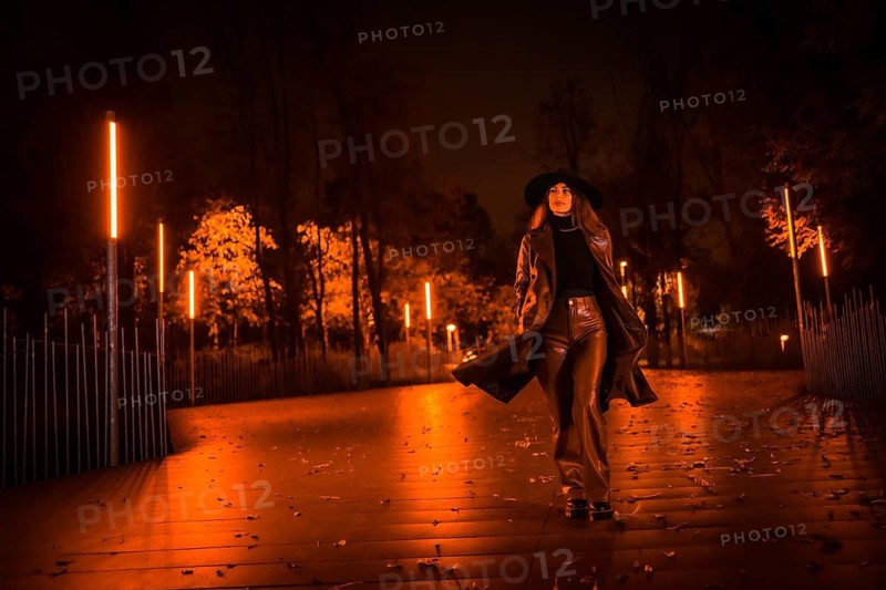 Girl in a hat walking calmly through a park on a winter night. Enjoying the solitude of the night in a fashionable pose